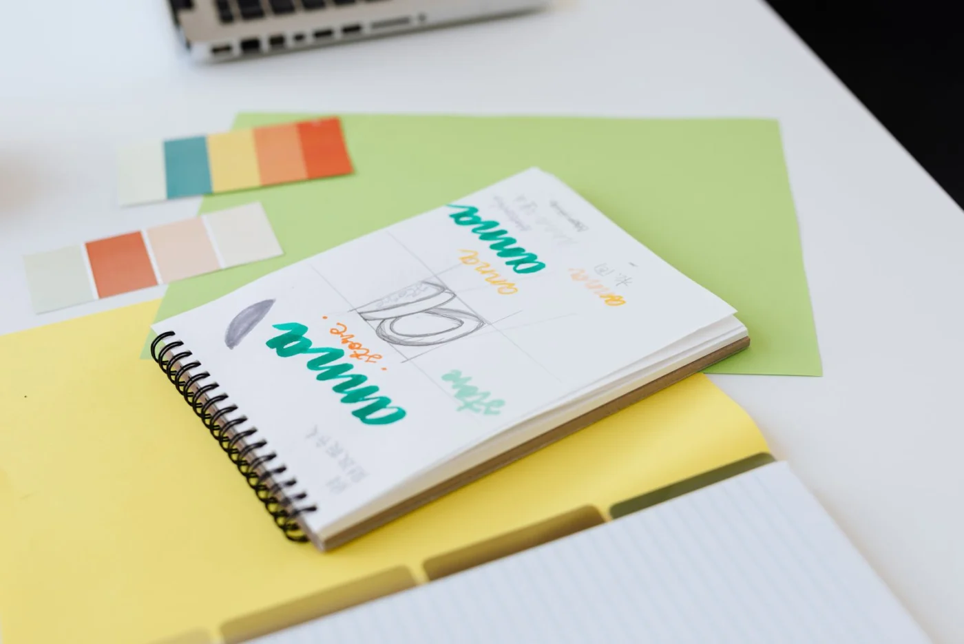 Branding sketches and colour swatches in a notebook on a desk