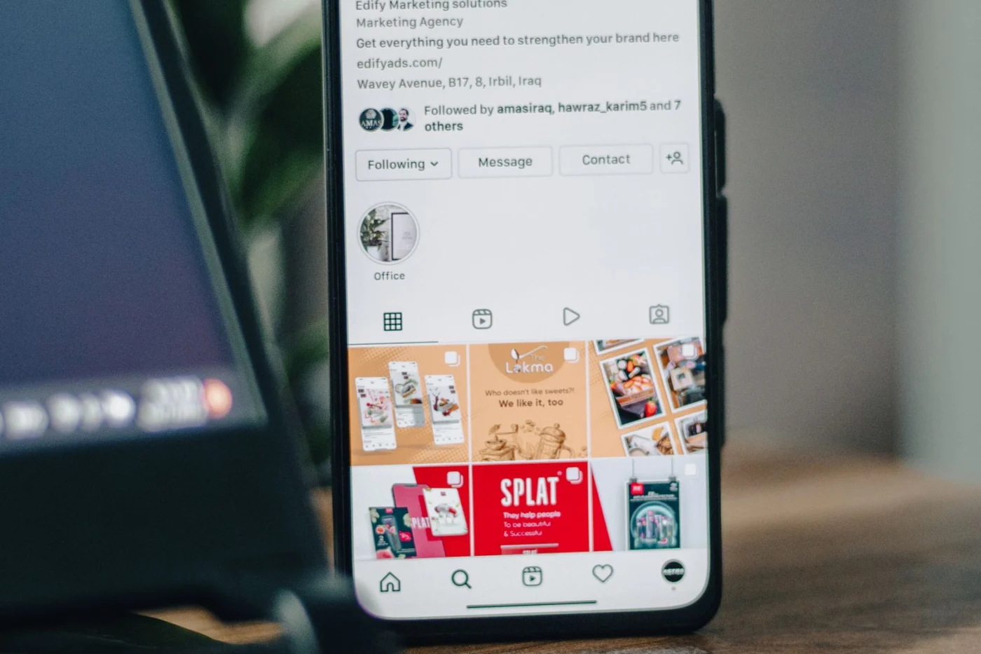 Instagram business profile open on a smartphone next to a laptop