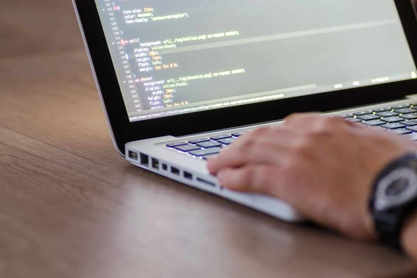Hands typing website code on a laptop
